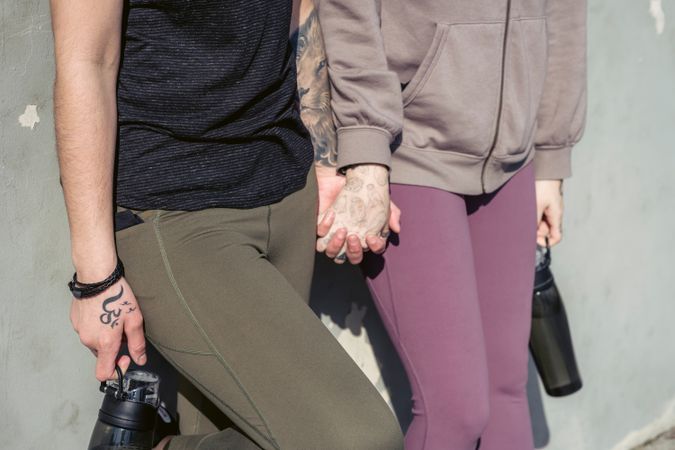 Cropped image of two women in leggings walking and holding hands
