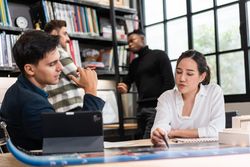 Female architect leading meeting on plans with colleague