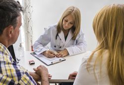 Female doctor writing prescription to a couple