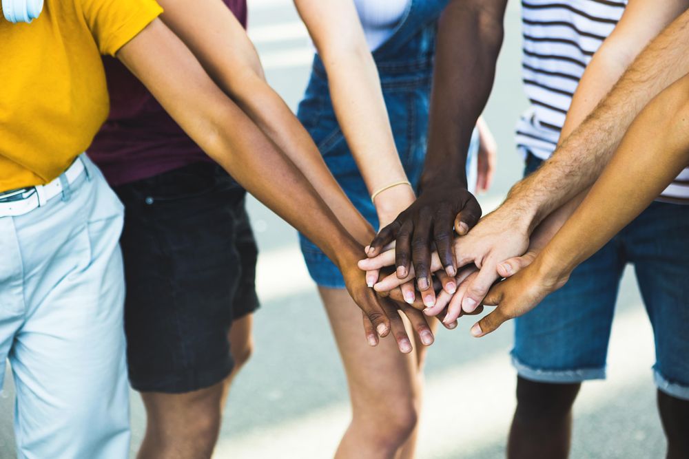 Close up multi ethnic group of students stacking hands together
