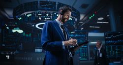 Low Angle Portrait of an Energetic Stock Exchange Manager Working in Modern Office.