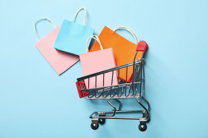 Shop cart with paper bags on blue background