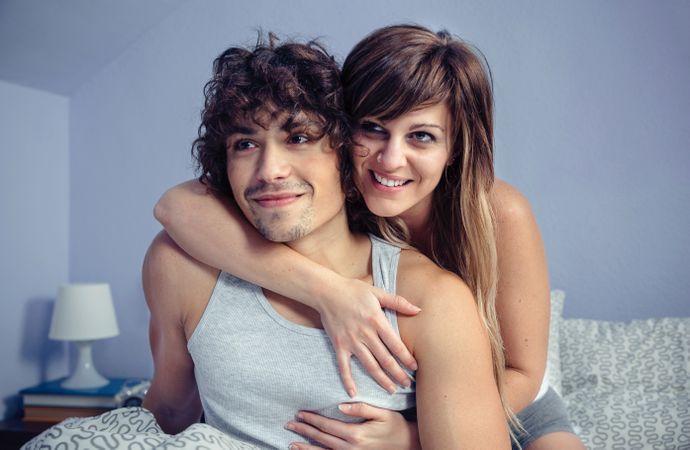 Happy couple embracing and smiling in bedroom