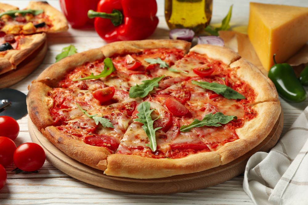 Tasty pizza and ingredients on wooden background