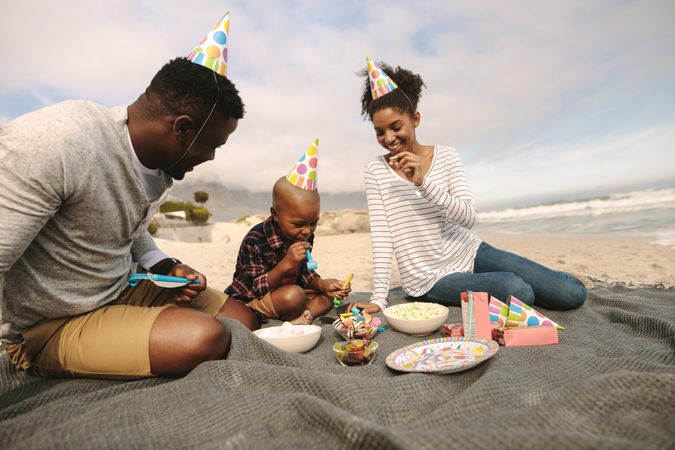 Beautiful family having party at the beach, with food on the picnic plaid