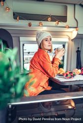 Vertical composition of woman sipping coffee in back of camper van 4dNDL0