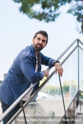Serious man in denim leaning on outdoor stairs rail bDrkr5