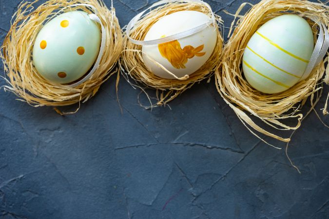Three pastel decorative eggs in nests with space for text