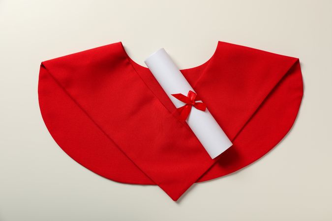 Cape of a graduate with a diploma, on a plain background.