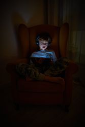 Curious boy playing on tablet in darkness