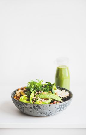 Healthy vegetarian bowl on light background, with smoothie, vertical composition, copy space