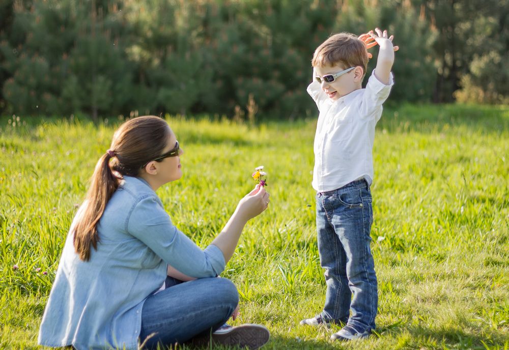 Son giving a bouquet of flowers to his pregnant mother in a field