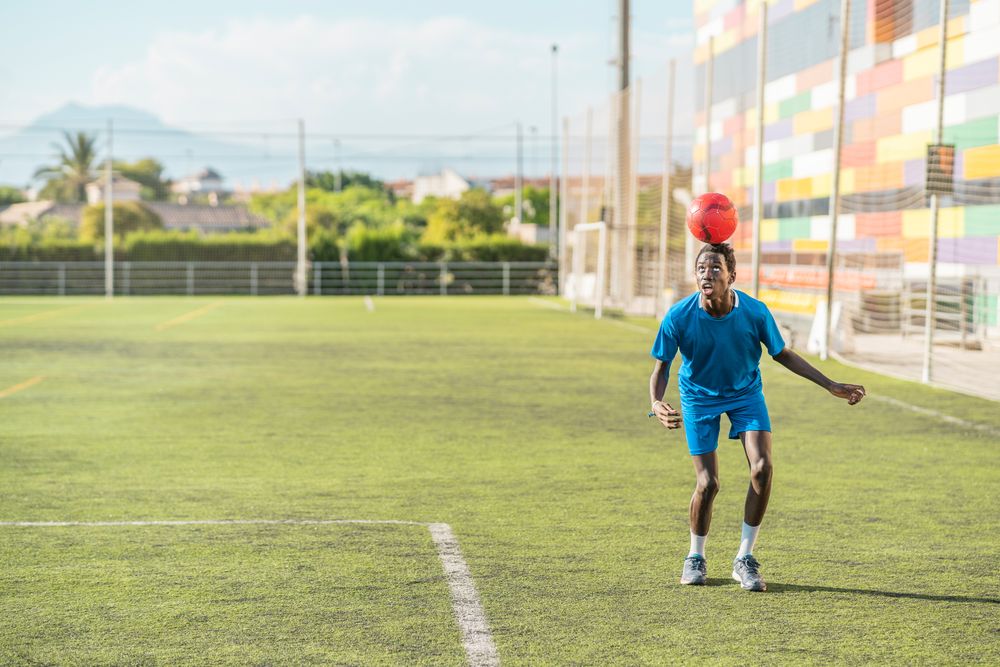 Black teenager jugging football ball on head