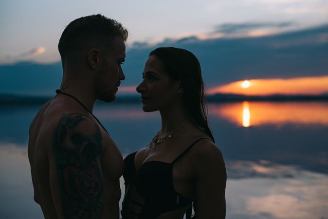 Couple hugging on beach of lake at sunset