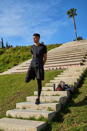 Hispanic sportsman stretching legs on stairs