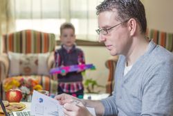 Father working in home office and son playing