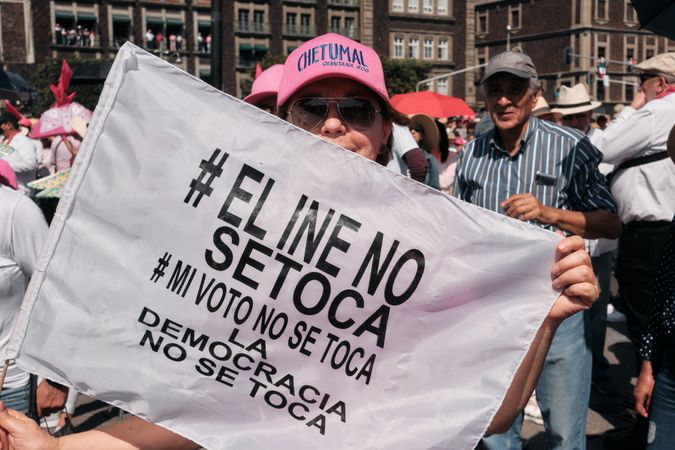 Mexico City, Mexico - February 26th, 2022: Woman in pink cap holding protest flag