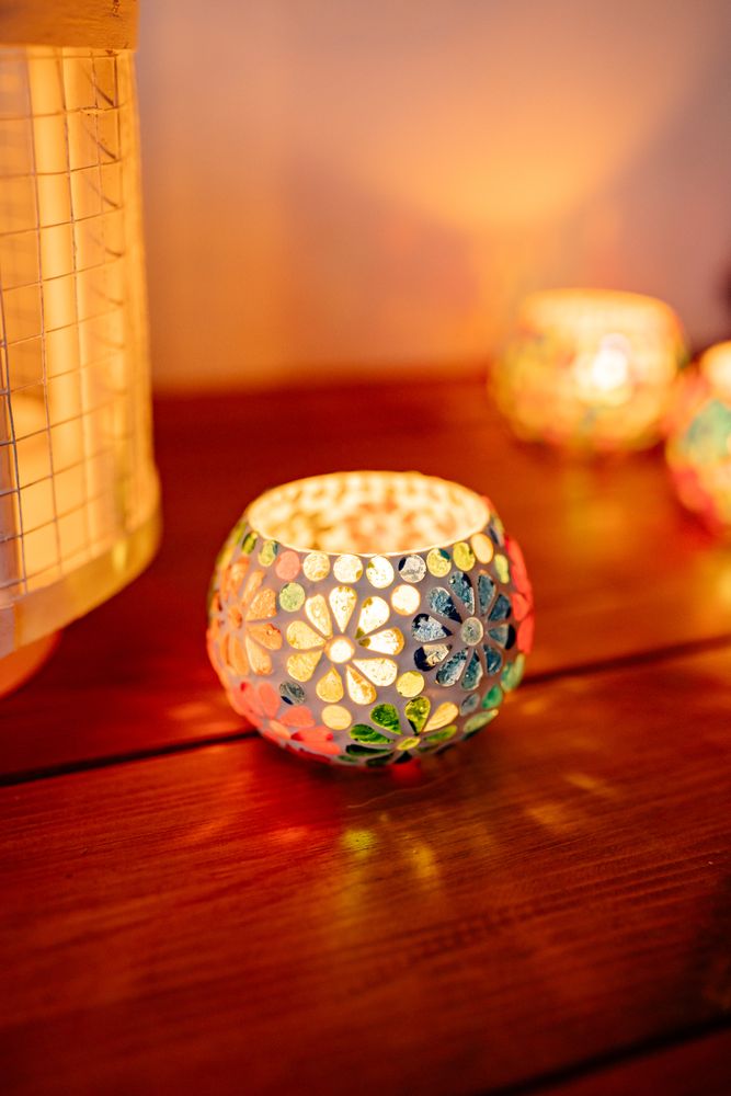 Lit candles in floral ornament on wooden table