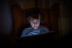 Boy playing on tablet in obscure room
