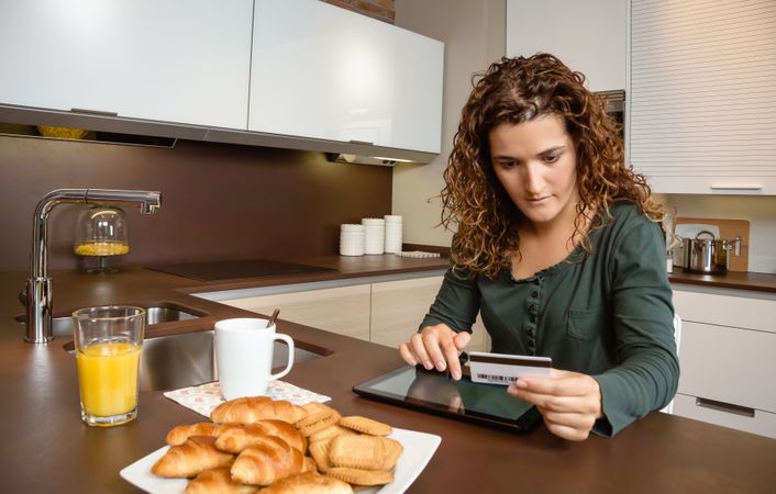Woman buying something on tablet over breakfast