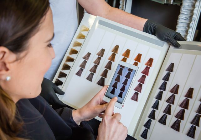 Woman comparing hair swatches on phone to book