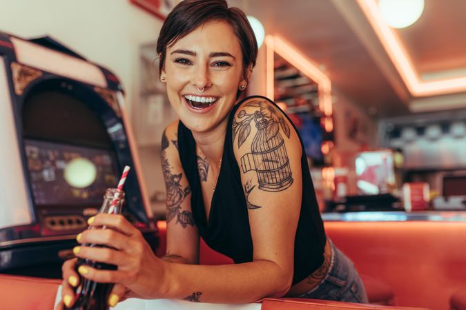 Smiling woman with tattooed arms standing in a diner