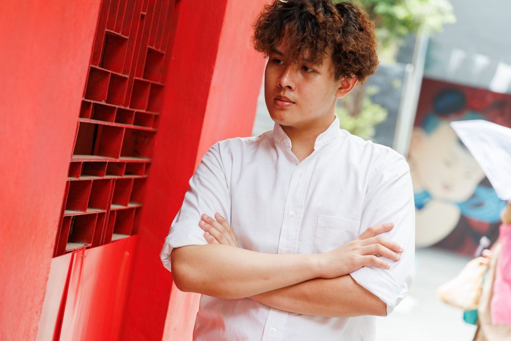 Portrait of Asian man in button up shirt standing with arms crossed