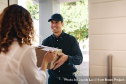 Smiling delivery man handing over a box to female at home 4BM7x5