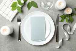 Composition of table setting with candles, leaves and cutlery on gray background