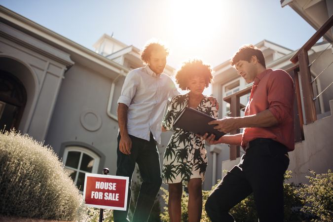 Outdoor shot of real estate agent with couple buying new house