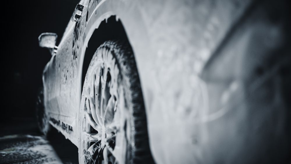 Close Up Shot of Foam Dripping from Car's Rear Wheel Arch onto the Electric Car's Tyre and Rim