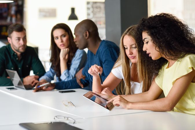 Group of male and female colleagues studying with tablet and laptop computer on desk