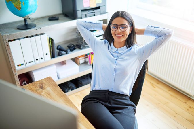 Happy female smiling and leaning back at her desk in her office