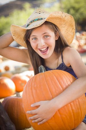 Preteen Girl Holding A Large Pumpkin at the Pumpkin Patch.