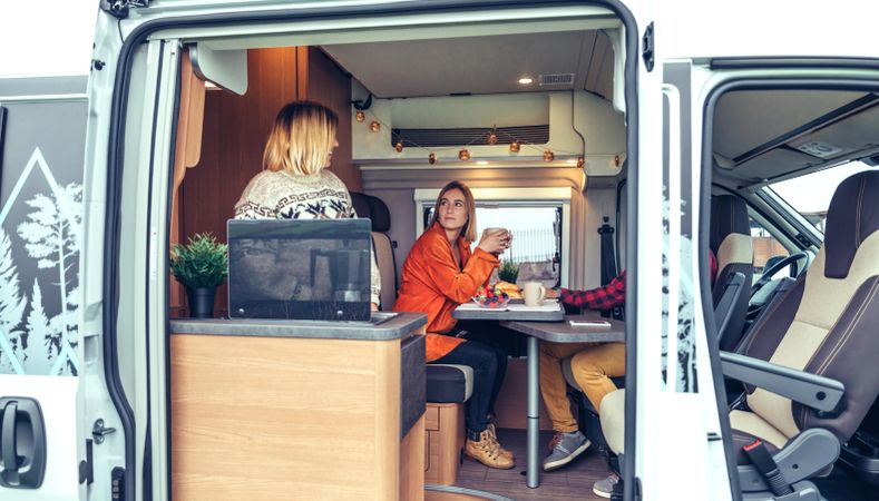 Women in warm sweaters having breakfast in back of van