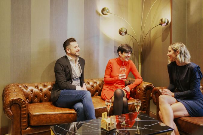 Group of friends enjoying drinks on leather sofa’s in lounge