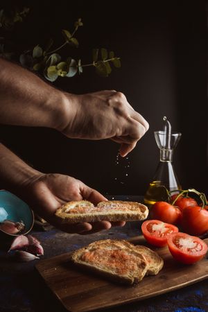 Crop person pouring salt on toasts