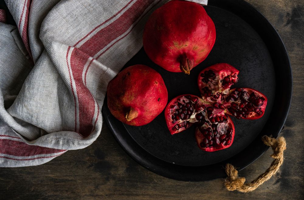 Top view of dark bowl full of fresh whole pomegranates
