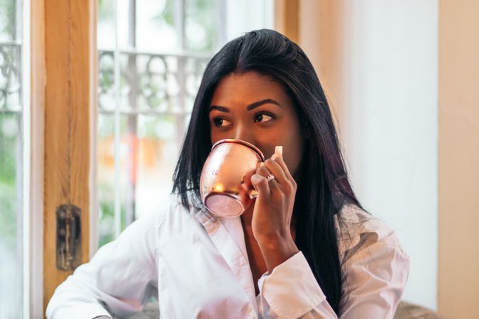 Black Latina woman having a drink in an indoor space