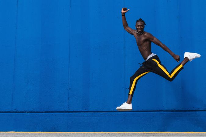 Cheerful Black man jumping on street