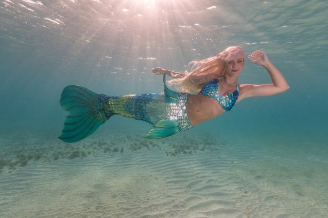 Blond fairytale female mermaid swimming underwater