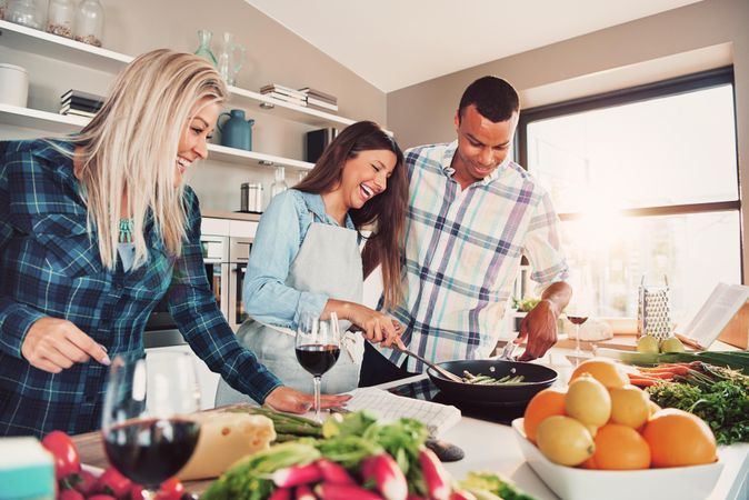 Group of friends cooking asparagus while drinking red wine