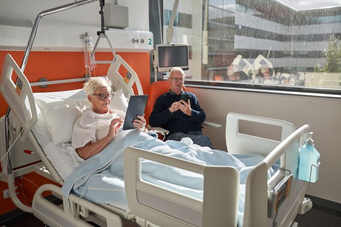 sick woman lying on couch with tablet near husband in ho