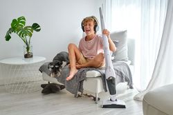 Boy with vacuum cleaner singing near dog