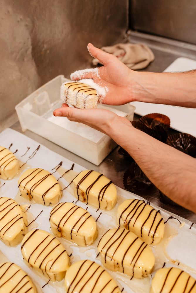 Crop confectioner covering pastry with coconut flakes