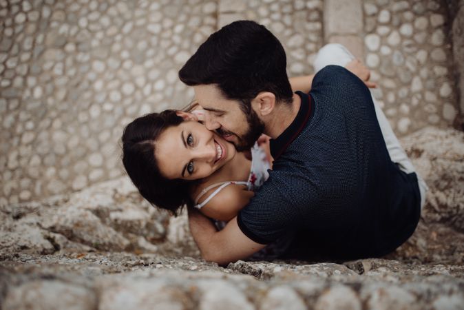 Happy couple kissing while sitting on stone street
