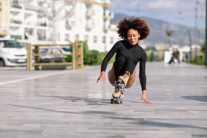 Black female with afro doing one leg tricks on roller skates
