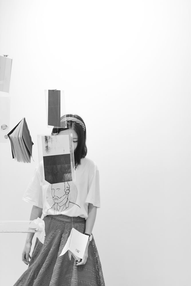 Grayscale photo of woman in front of floating books
