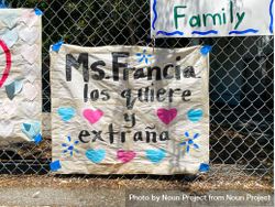 Homemade sign from a teacher to her students in Spanish taped to school fence 4MGLE0