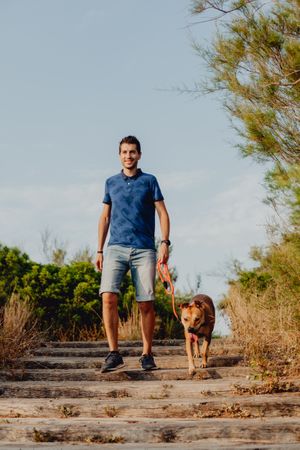 Happy adult man walking with dog along rural pathway